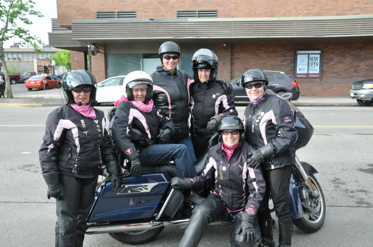 Members of Women in the Wind, a women's motorcycle riding group, posing around a bike. 