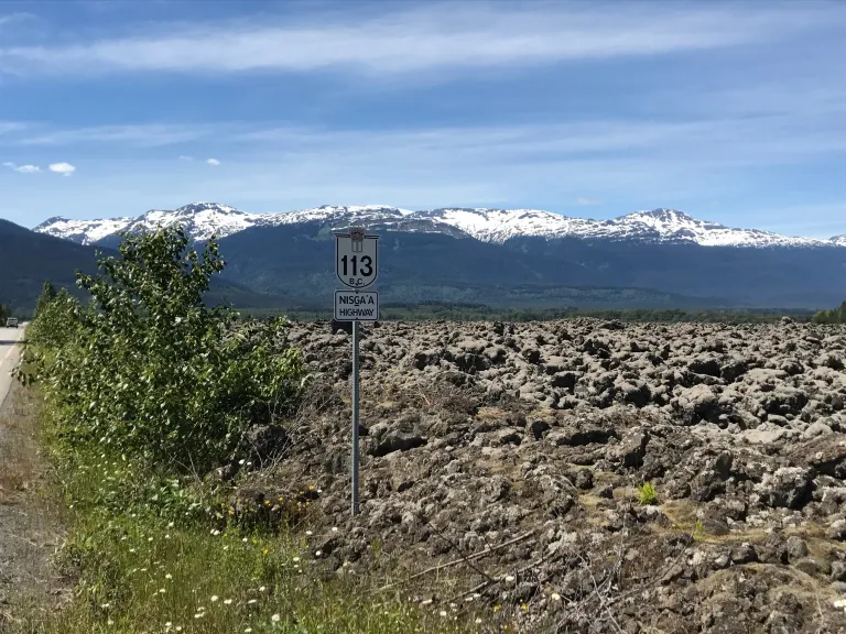 Niga'a Highway sign beside the Nass Valley's lava beds with mountains in the background