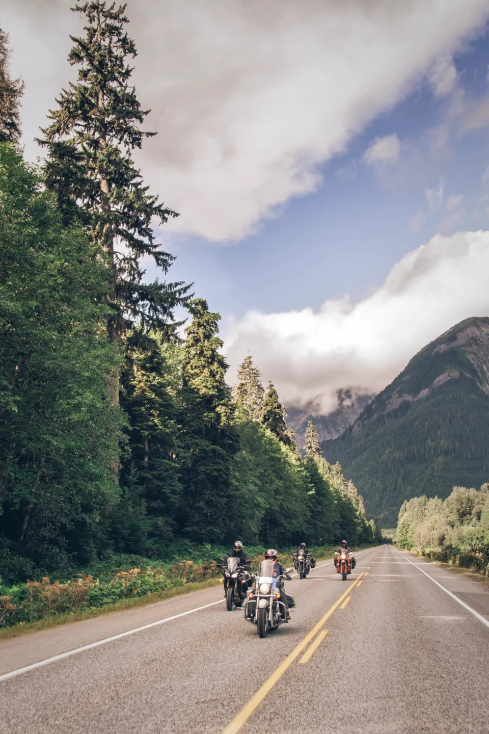 motorcyclists riding toward the endless rock wall by the Skeena River on Route 16 from Terrace to Prince Rupert